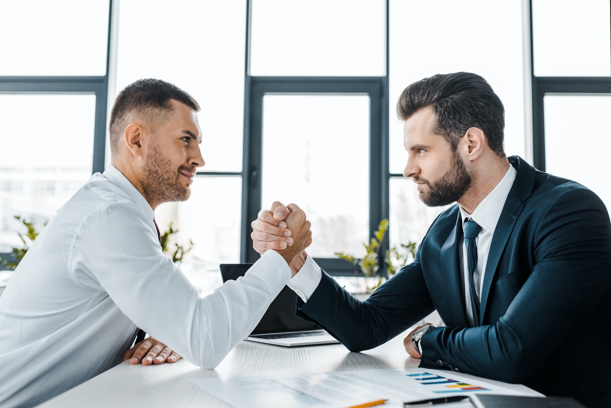 handsome businessmen competing arm wrestling in modern office